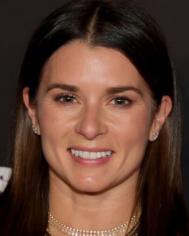 Danica Patrick poses in a pink velour blazer and smiles for the camera.
